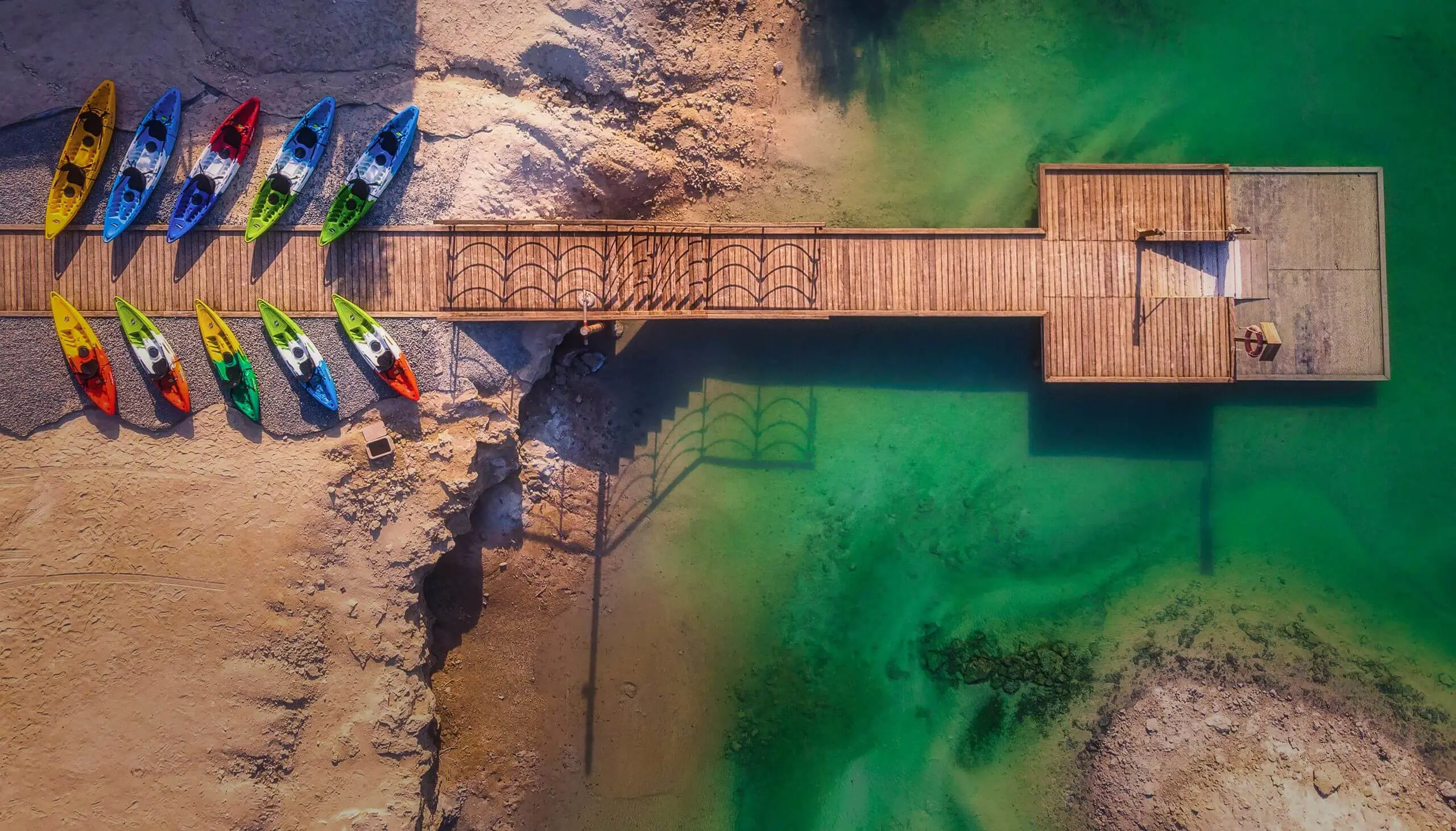 Aerial view of a wooden walkway over clear turquoise waters on Jubail Island.
