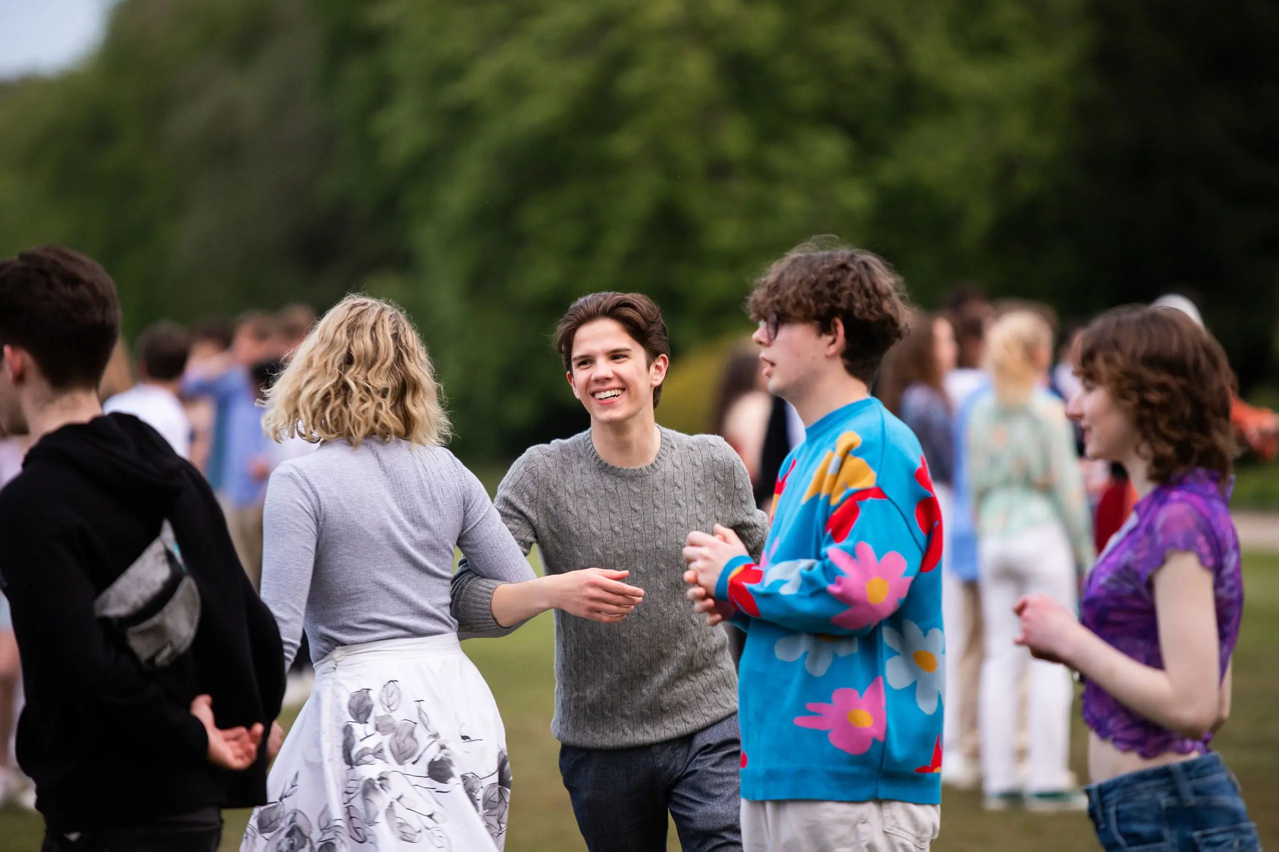 Group of Gordonstoun alumni and students smiling and conversing outdoors.
