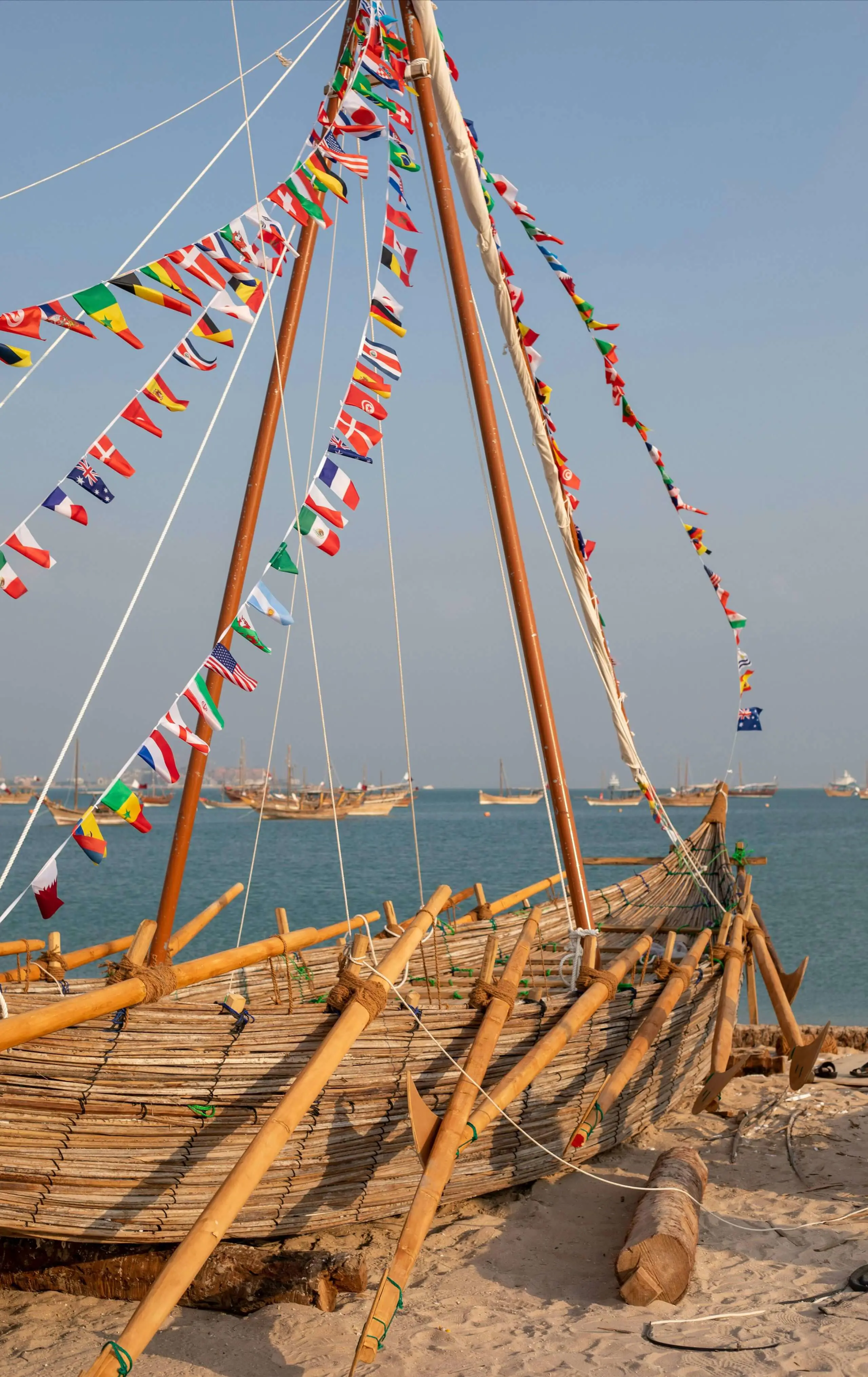 Wooden traditional boat rigged with colorful prayer flags docked near coastal waters.